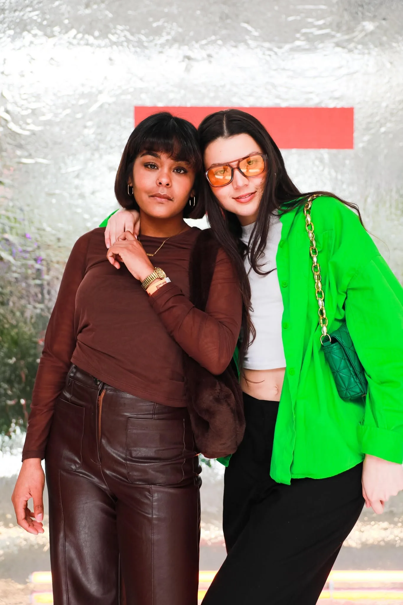 Two guests posing together in front of a silver wall at a SPACES event